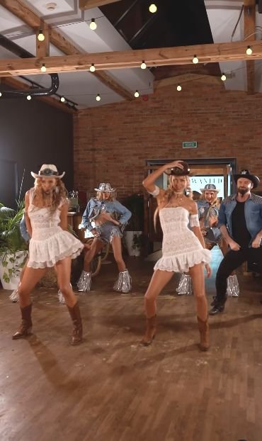 Line dancers in white dresses and cowboy hats